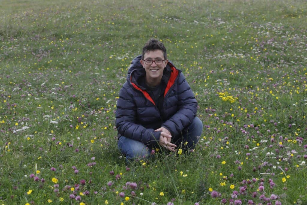 Rhoda kneeling in the Machair flowers in Tiree